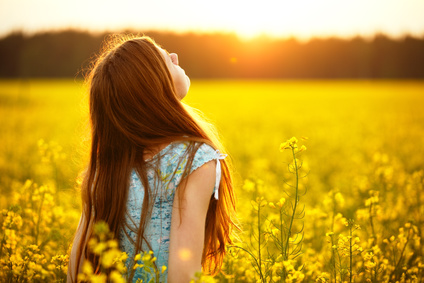 Young woman enjoying sunlight in canola field